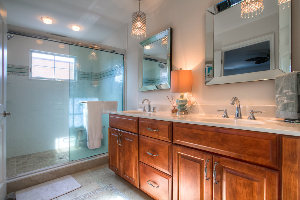 This is an example of a beach style bathroom in Philadelphia with an integrated sink, medium wood cabinets, solid surface worktops, an alcove shower, multi-coloured tiles, ceramic tiles, white walls, ceramic flooring and raised-panel cabinets.
