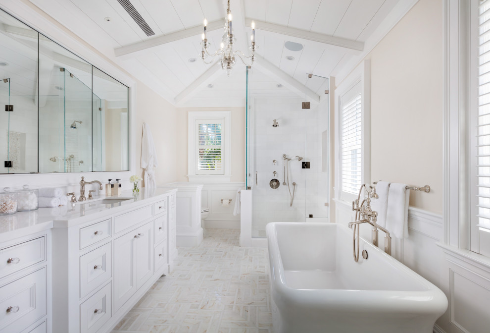 Photo of a world-inspired ensuite bathroom in Miami with recessed-panel cabinets, white cabinets, a freestanding bath, an alcove shower, beige walls, a submerged sink, multi-coloured floors, a hinged door and white worktops.