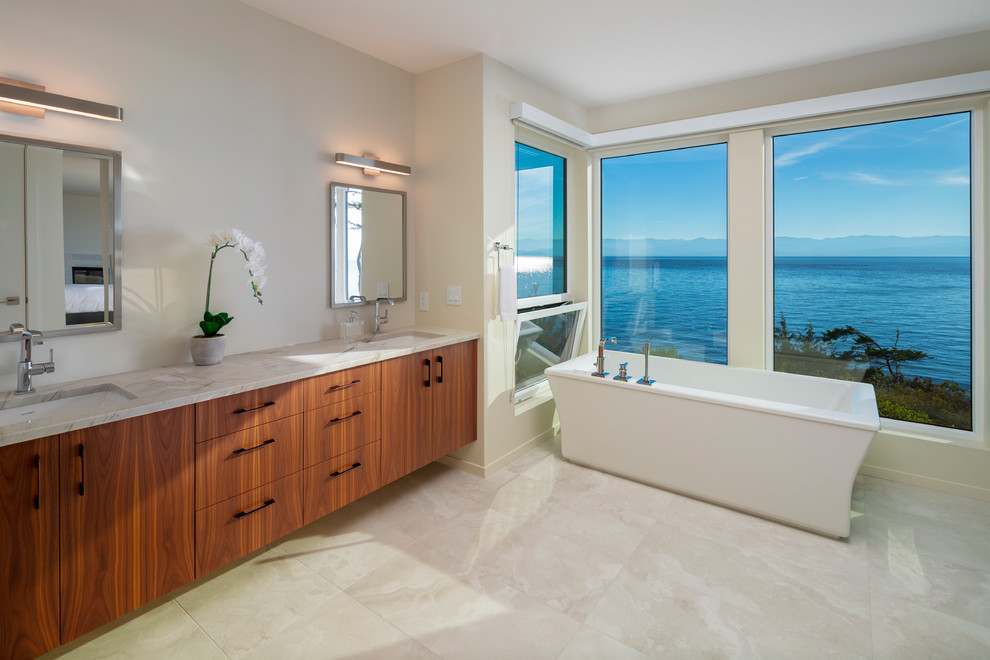 Contemporary bathroom in Other with flat-panel cabinets, medium wood cabinets, a freestanding bath, white walls, a submerged sink, white floors and beige worktops.