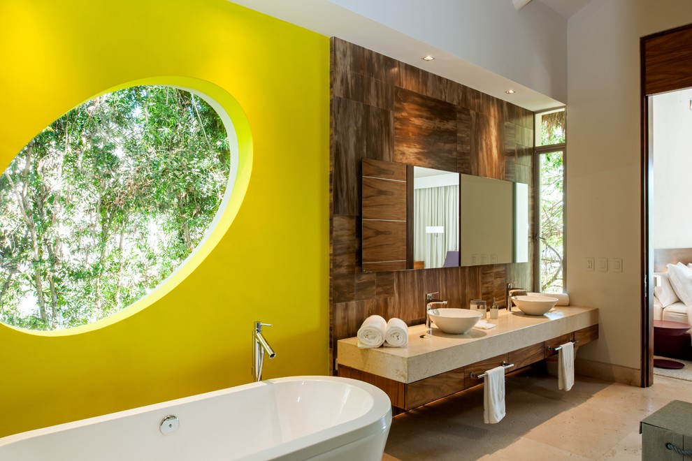 Inspiration pour une salle de bain design en bois foncé avec un placard à porte plane, une baignoire indépendante, un mur jaune et une vasque.