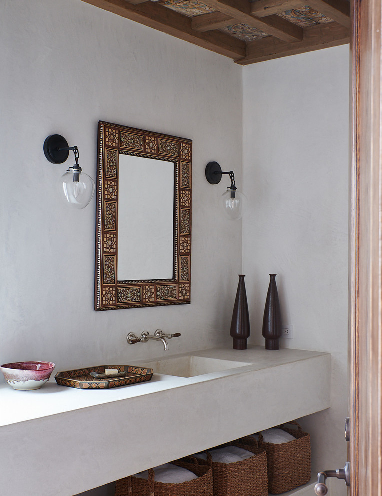 Mediterranean bathroom in Santa Barbara with open cabinets, white walls, an integrated sink and white worktops.