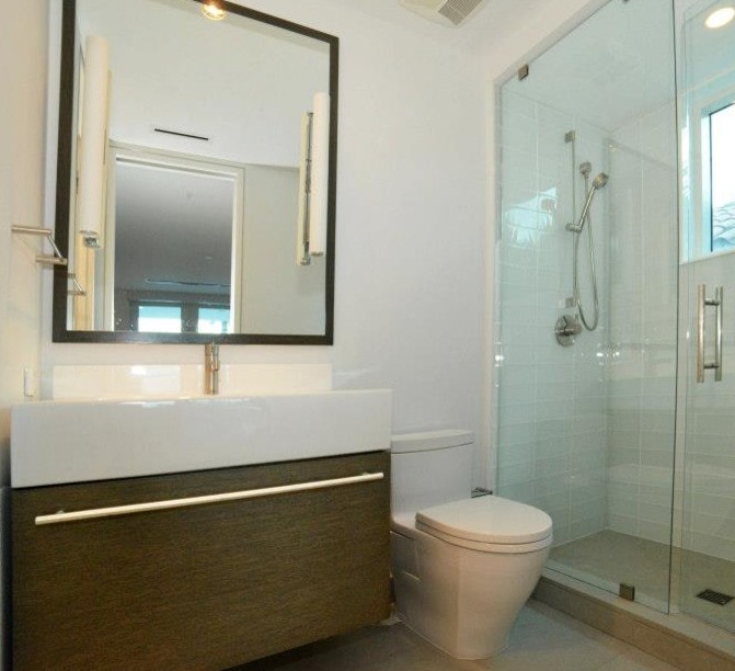 Doorless shower - mid-sized modern 3/4 white tile and glass tile porcelain tile doorless shower idea in Miami with an integrated sink, furniture-like cabinets, dark wood cabinets, quartz countertops, a one-piece toilet and white walls