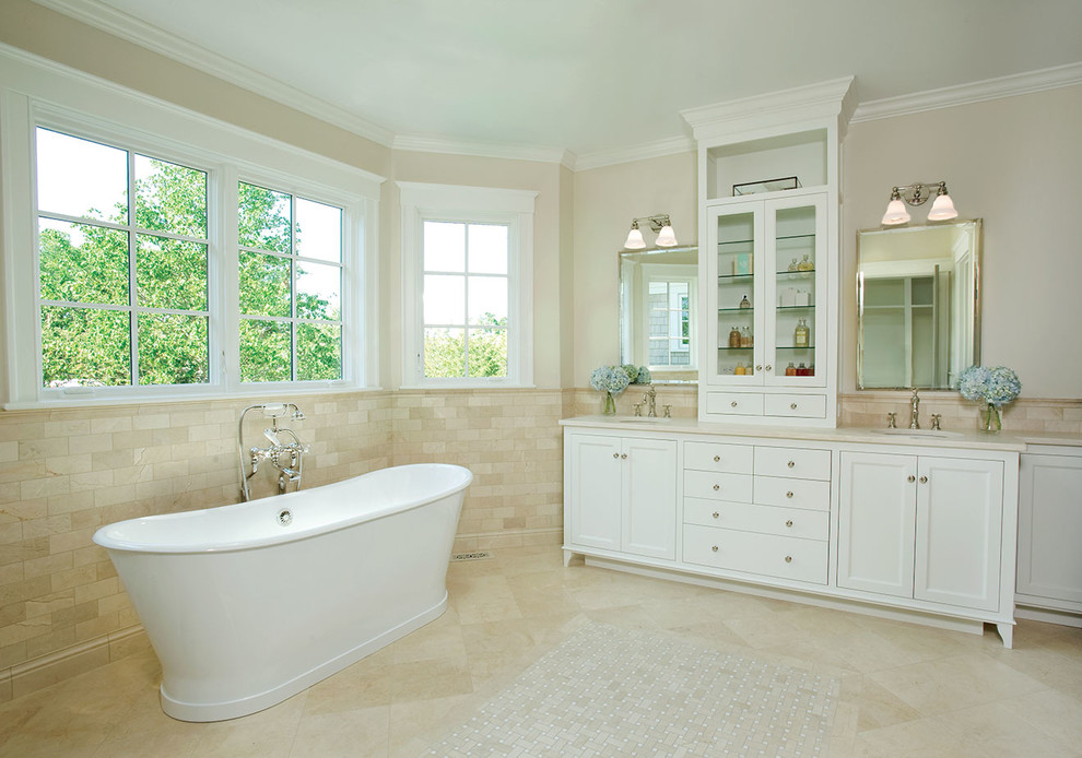 Photo of a medium sized traditional ensuite bathroom in Boston with recessed-panel cabinets, white cabinets, a freestanding bath, beige tiles, stone tiles, beige walls, marble flooring, a submerged sink and marble worktops.