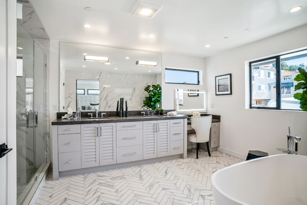 Inspiration for a transitional master white tile white floor bathroom remodel in Los Angeles with louvered cabinets, white cabinets, white walls, an undermount sink, a hinged shower door and gray countertops