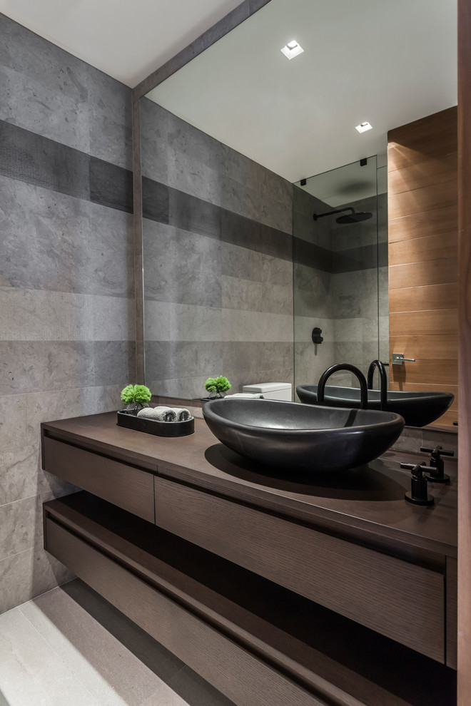 Inspiration for a contemporary gray tile gray floor alcove shower remodel in Miami with flat-panel cabinets, dark wood cabinets, a vessel sink, wood countertops and brown countertops
