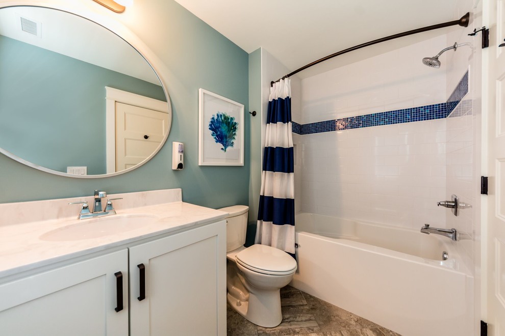 他の地域にあるお手頃価格の中くらいなトランジショナルスタイルのおしゃれなバスルーム (浴槽なし) (シェーカースタイル扉のキャビネット、白いキャビネット、シャワー付き浴槽	、分離型トイレ、青いタイル、白いタイル、サブウェイタイル、グレーの壁、ラミネートの床、アンダーカウンター洗面器、大理石の洗面台、茶色い床、シャワーカーテン) の写真