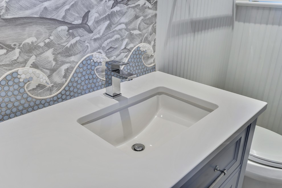 На фото: ванная комната среднего размера в морском стиле с синими фасадами, унитазом-моноблоком, разноцветной плиткой, керамической плиткой, синими стенами, полом из керамической плитки, душевой кабиной, столешницей из гранита, белым полом, душем с распашными дверями и белой столешницей