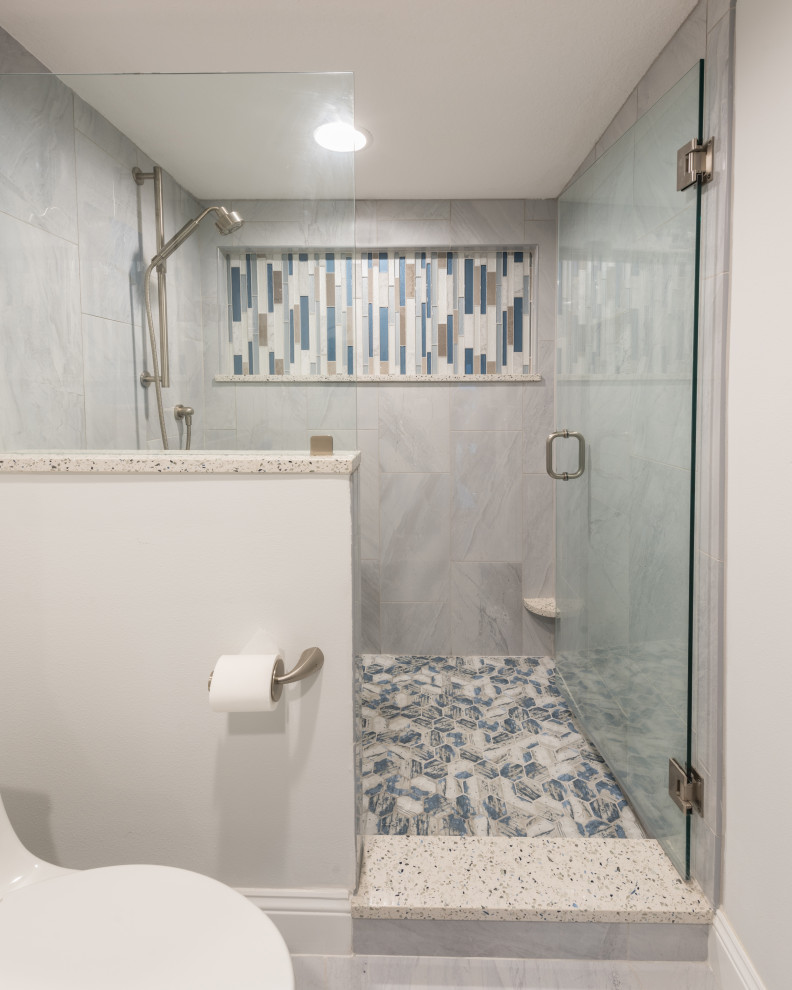 Foto på ett mellanstort maritimt vit en-suite badrum, med luckor med infälld panel, vita skåp, en dusch i en alkov, grå kakel, porslinskakel, grå väggar, klinkergolv i porslin, ett undermonterad handfat, bänkskiva i återvunnet glas, grått golv och dusch med gångjärnsdörr