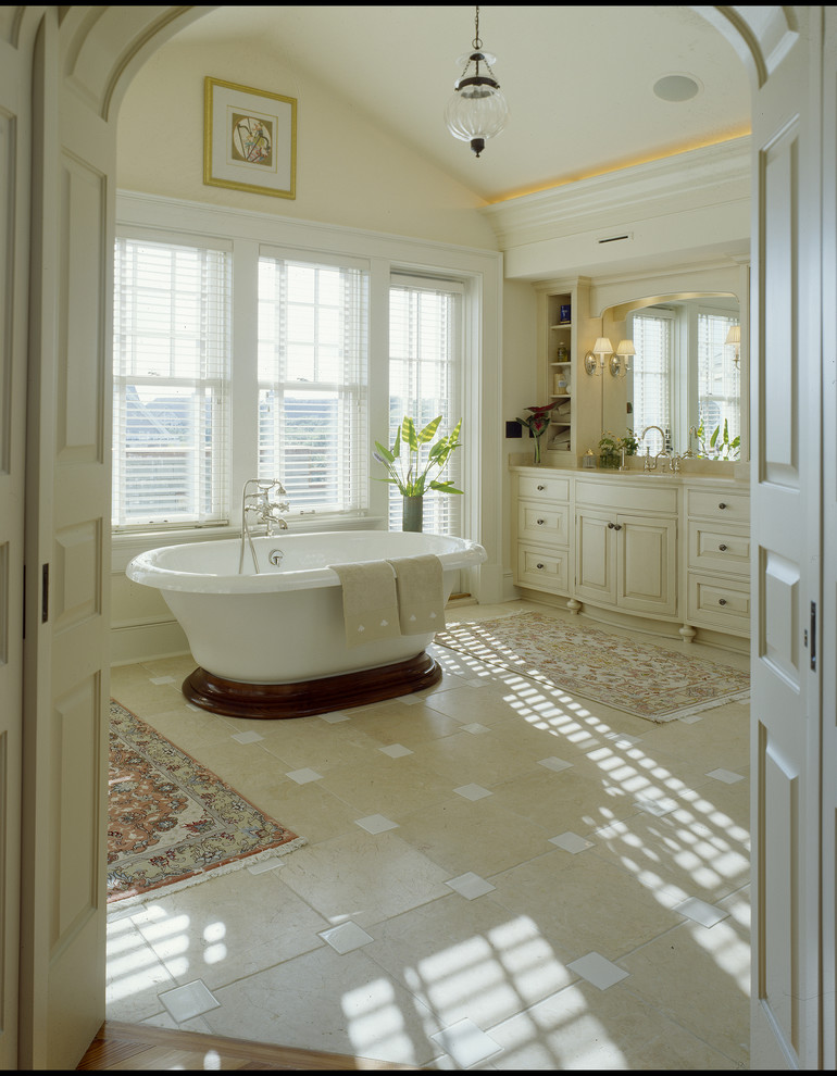 Bathroom - large coastal master beige tile and porcelain tile limestone floor bathroom idea in Charleston with a drop-in sink, raised-panel cabinets, beige cabinets, limestone countertops, a one-piece toilet and yellow walls