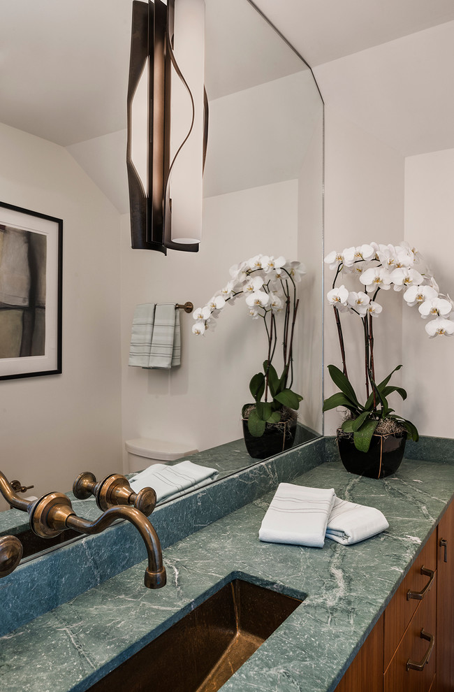 Immagine di una stanza da bagno design con lavabo sottopiano, ante lisce, ante in legno scuro, top in marmo e pareti bianche