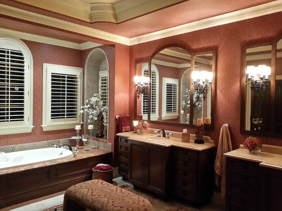 На фото: большая главная ванная комната в средиземноморском стиле с врезной раковиной, фасадами с декоративным кантом, темными деревянными фасадами, столешницей из известняка, накладной ванной, разноцветной плиткой, керамической плиткой, красными стенами и полом из известняка
