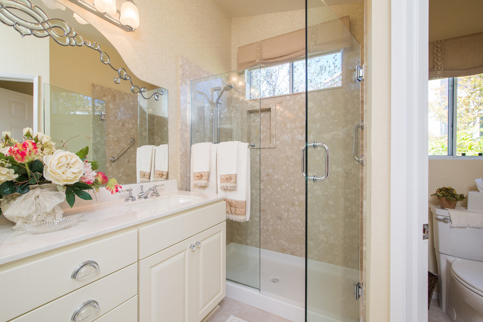 Inredning av ett klassiskt mellanstort badrum med dusch, med ett undermonterad handfat, luckor med upphöjd panel, vita skåp, marmorbänkskiva, en dusch i en alkov, en toalettstol med hel cisternkåpa och beige väggar