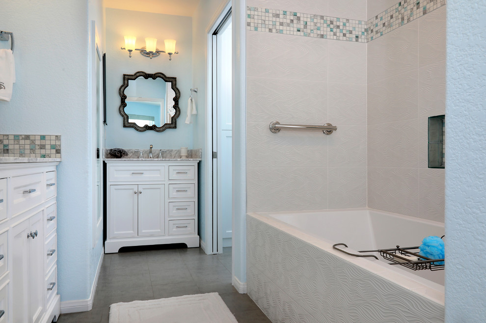 Aménagement d'une salle de bain principale bord de mer de taille moyenne avec un placard à porte shaker, des portes de placard blanches, une baignoire en alcôve, un combiné douche/baignoire, WC séparés, un carrelage bleu, des carreaux de porcelaine, un mur bleu, un sol en carrelage de porcelaine, un plan de toilette en marbre, un sol gris et un lavabo encastré.