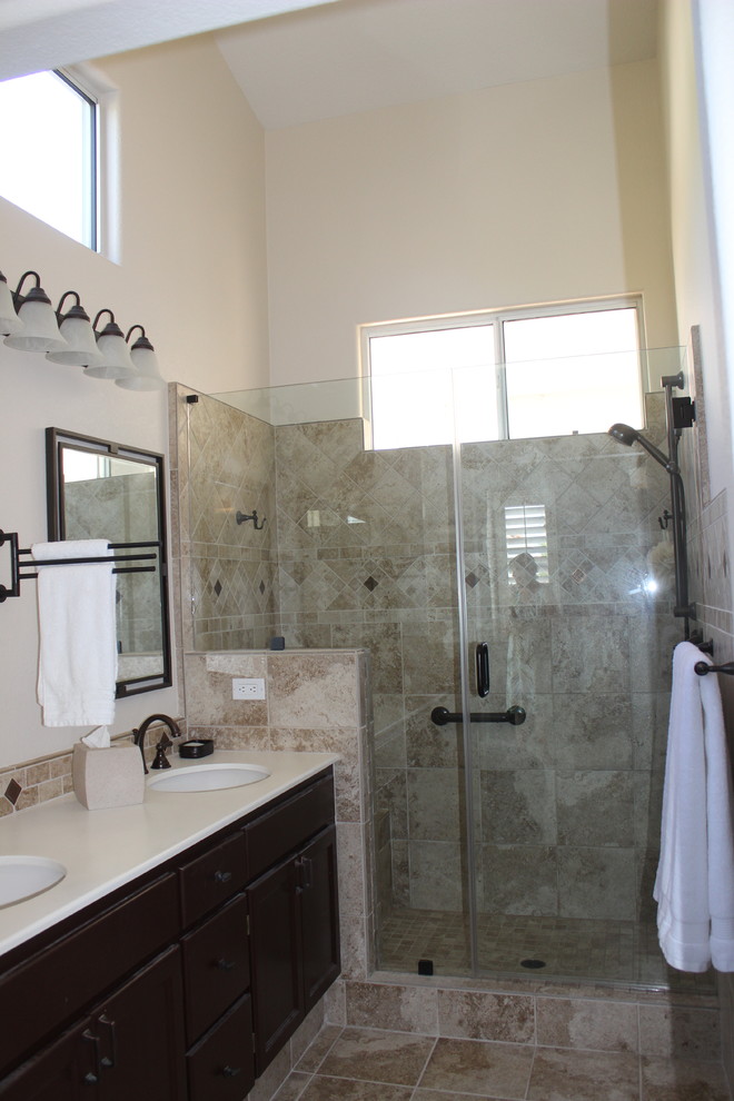 Ejemplo de cuarto de baño clásico renovado con lavabo integrado, armarios con paneles lisos, puertas de armario de madera en tonos medios, encimera de acrílico, ducha esquinera, baldosas y/o azulejos marrones, baldosas y/o azulejos de cerámica y paredes beige