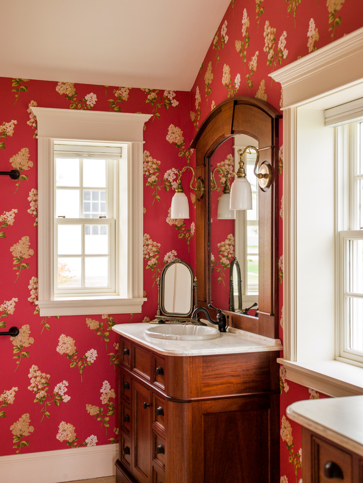 Exemple d'une grande salle d'eau chic en bois foncé avec un placard à porte affleurante, un carrelage beige, des carreaux de porcelaine, un mur rouge, un sol en carrelage de porcelaine, un lavabo posé et un plan de toilette en marbre.