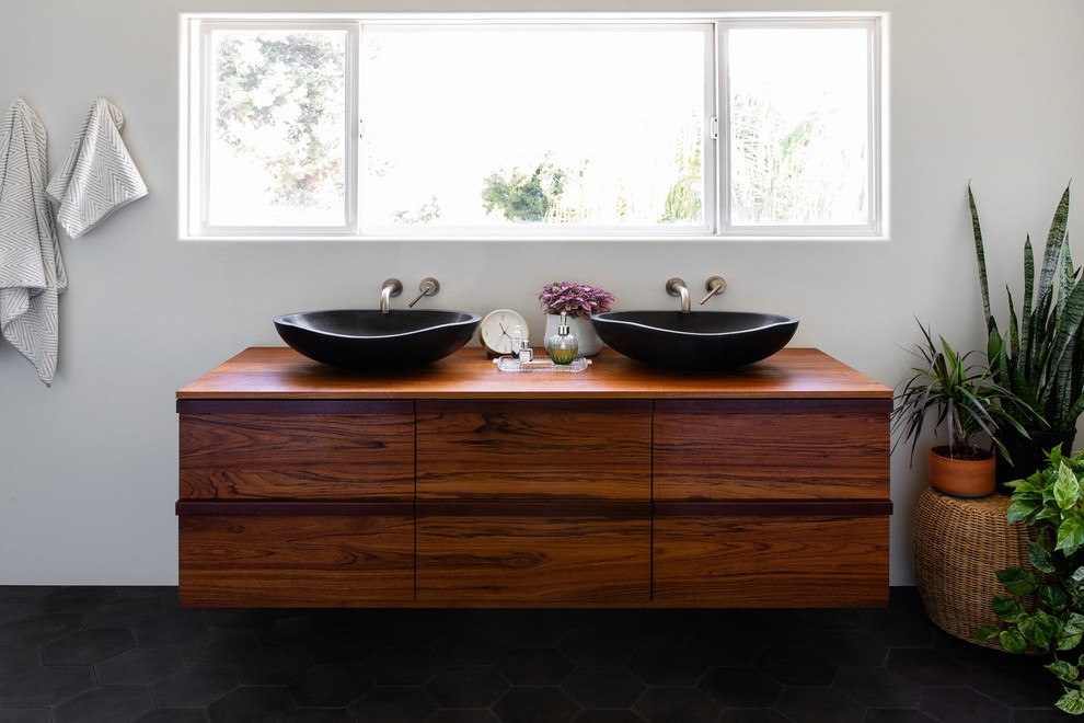 Inspiration pour une grande salle de bain principale design en bois foncé avec un placard à porte plane, un mur blanc, carreaux de ciment au sol, une vasque, un plan de toilette en bois, un sol noir et un plan de toilette marron.