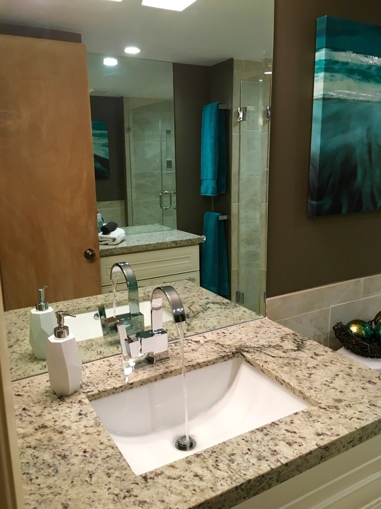 Large island style 3/4 gray tile and porcelain tile pebble tile floor and beige floor alcove shower photo in Other with raised-panel cabinets, white cabinets, a two-piece toilet, gray walls, an undermount sink, a hinged shower door, granite countertops and gray countertops