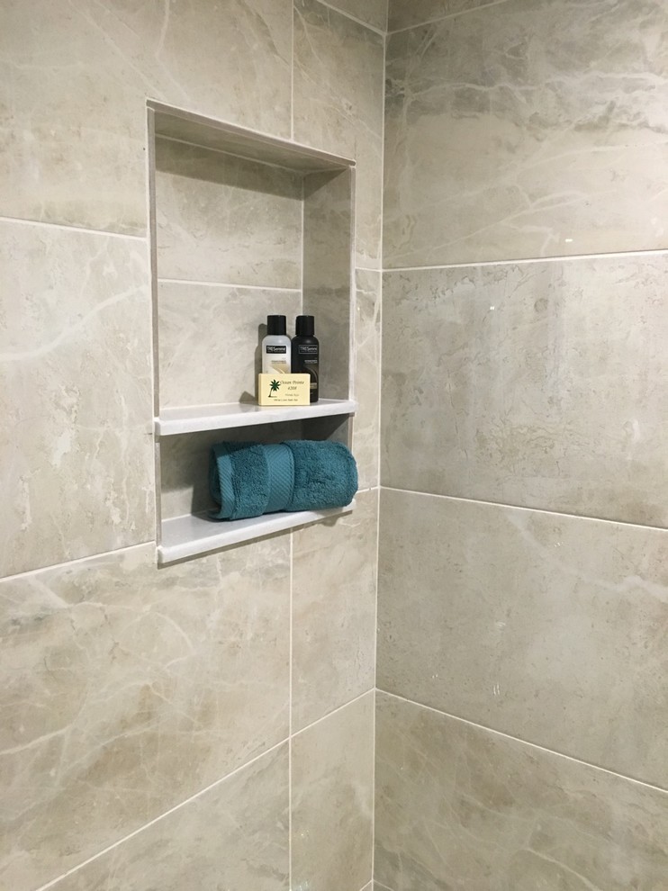 Bild på ett stort tropiskt grå grått badrum med dusch, med luckor med upphöjd panel, vita skåp, en dusch i en alkov, en toalettstol med separat cisternkåpa, grå kakel, porslinskakel, grå väggar, klinkergolv i småsten, ett undermonterad handfat, granitbänkskiva, dusch med gångjärnsdörr och beiget golv