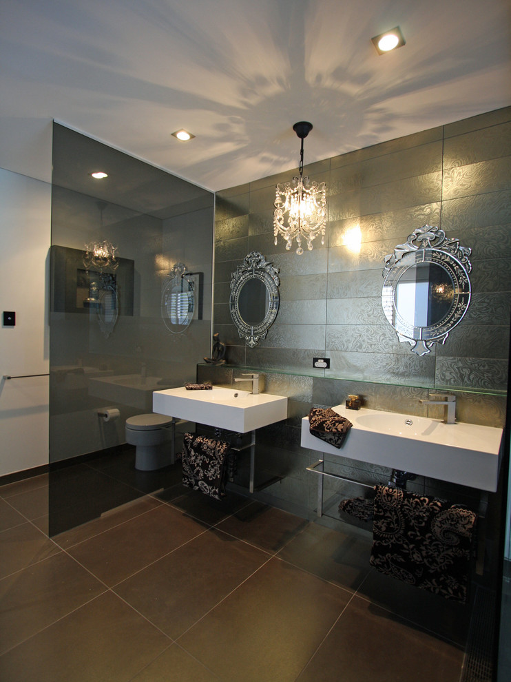 Eklektisk inredning av ett stort en-suite badrum, med luckor med glaspanel, ett fristående badkar, våtrum, grå kakel, kakel i metall, klinkergolv i porslin, ett väggmonterat handfat och bänkskiva i glas