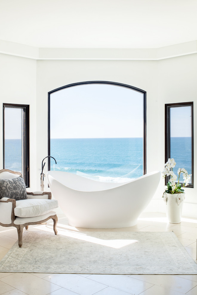 Пример оригинального дизайна: большая главная ванная комната в средиземноморском стиле с отдельно стоящей ванной, белыми стенами, полом из известняка и бежевым полом