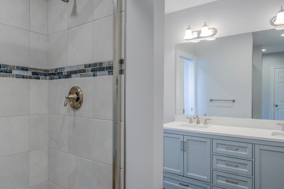 Foto på ett stort maritimt vit en-suite badrum, med luckor med infälld panel, vita skåp, en dusch i en alkov, vita väggar, mellanmörkt trägolv, ett undermonterad handfat, granitbänkskiva och dusch med skjutdörr