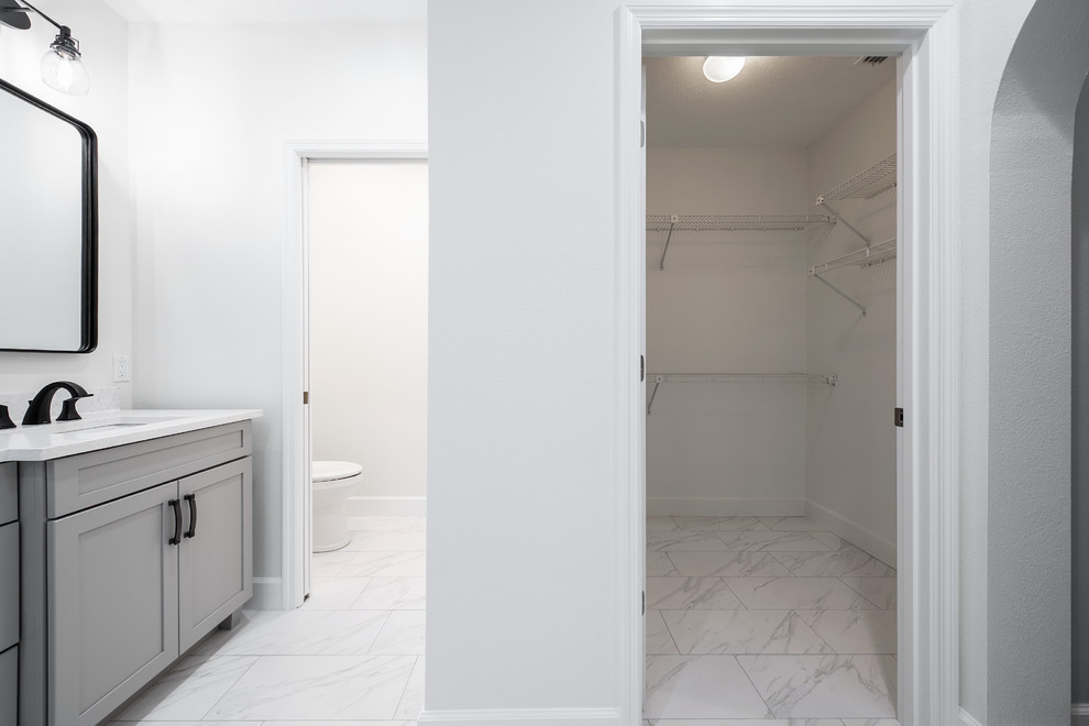 Идея дизайна: большая главная ванная комната в стиле неоклассика (современная классика) с фасадами в стиле шейкер, серыми фасадами, ванной на ножках, душем без бортиков, раздельным унитазом, белой плиткой, керамогранитной плиткой, серыми стенами, полом из керамогранита, врезной раковиной, столешницей из искусственного кварца, белым полом, душем с распашными дверями и белой столешницей