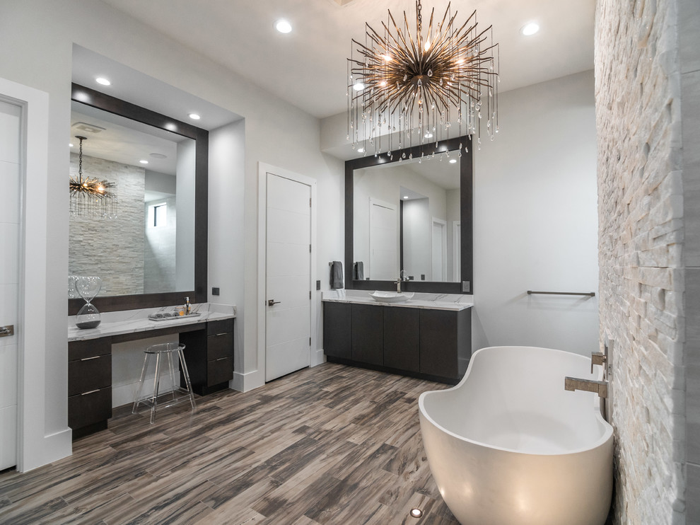 This is an example of an expansive contemporary ensuite bathroom in Tampa with flat-panel cabinets, black cabinets, a japanese bath, beige tiles, white tiles, stone tiles, white walls, medium hardwood flooring, a vessel sink, quartz worktops, brown floors and white worktops.