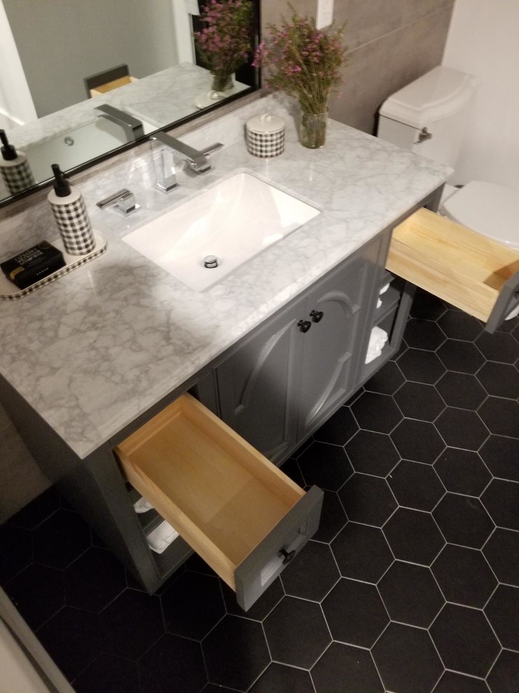 Small urban ensuite bathroom in Los Angeles with freestanding cabinets, grey cabinets, an alcove bath, a corner shower, a two-piece toilet, grey tiles, porcelain tiles, grey walls, ceramic flooring, a submerged sink, marble worktops, black floors, a hinged door and white worktops.