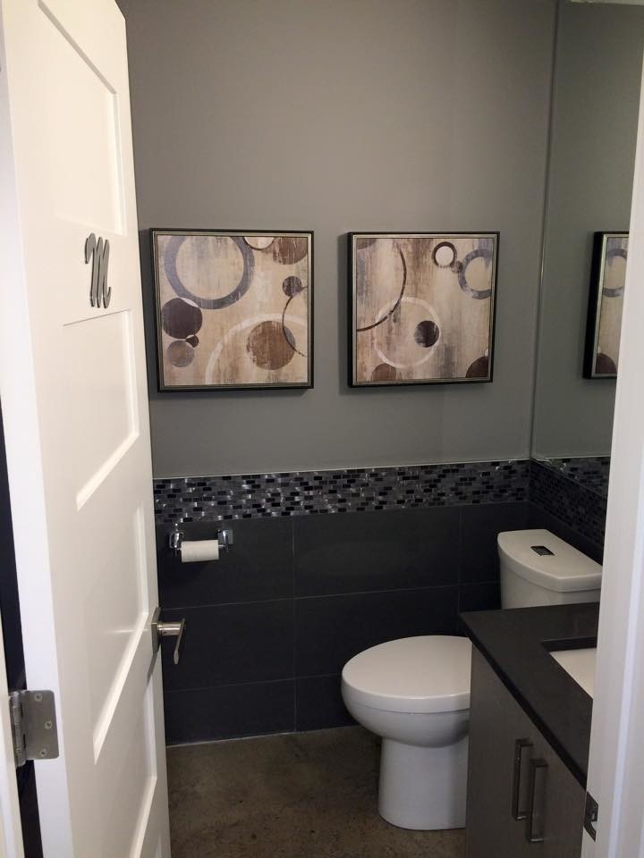 Cette image montre un petit WC et toilettes minimaliste avec un lavabo encastré, un placard à porte plane, des portes de placard grises, un plan de toilette en quartz modifié, un carrelage noir, un mur gris et sol en béton ciré.