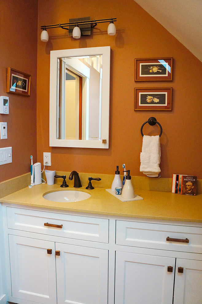 Inredning av ett klassiskt badrum, med ett undermonterad handfat, skåp i mellenmörkt trä, bänkskiva i kvarts, en dubbeldusch, en toalettstol med separat cisternkåpa, beige kakel, porslinskakel, orange väggar och klinkergolv i porslin