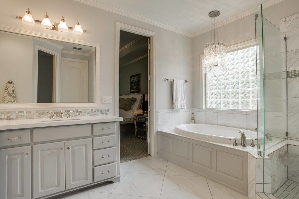 Klassisk inredning av ett stort en-suite badrum, med luckor med upphöjd panel, grå skåp, ett platsbyggt badkar, en hörndusch, svart och vit kakel, grå kakel, stenkakel, grå väggar, marmorgolv, ett undermonterad handfat och bänkskiva i kvartsit