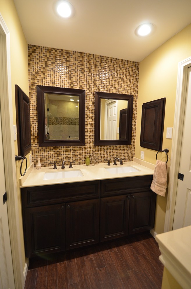 Пример оригинального дизайна: ванная комната среднего размера в стиле неоклассика (современная классика) с фасадами с выступающей филенкой, темными деревянными фасадами, коричневой плиткой, плиткой мозаикой, желтыми стенами, темным паркетным полом, душевой кабиной, врезной раковиной, столешницей из искусственного кварца и душем в нише
