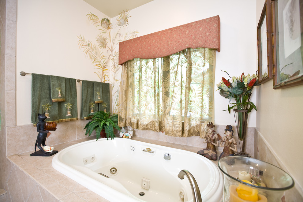 Immagine di una grande stanza da bagno padronale tropicale con vasca da incasso, piastrelle in pietra, top piastrellato e top beige
