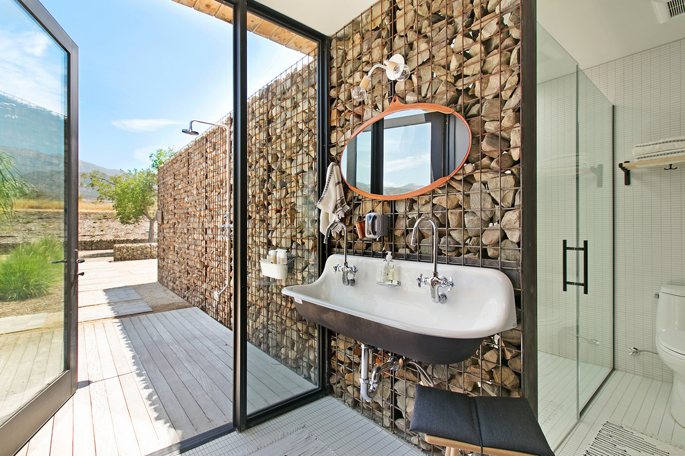 Modernes Badezimmer mit bodengleicher Dusche, Toilette mit Aufsatzspülkasten, weißen Fliesen, Mosaikfliesen, weißer Wandfarbe, Mosaik-Bodenfliesen, Wandwaschbecken, weißem Boden, Falttür-Duschabtrennung und Steinwänden in Los Angeles