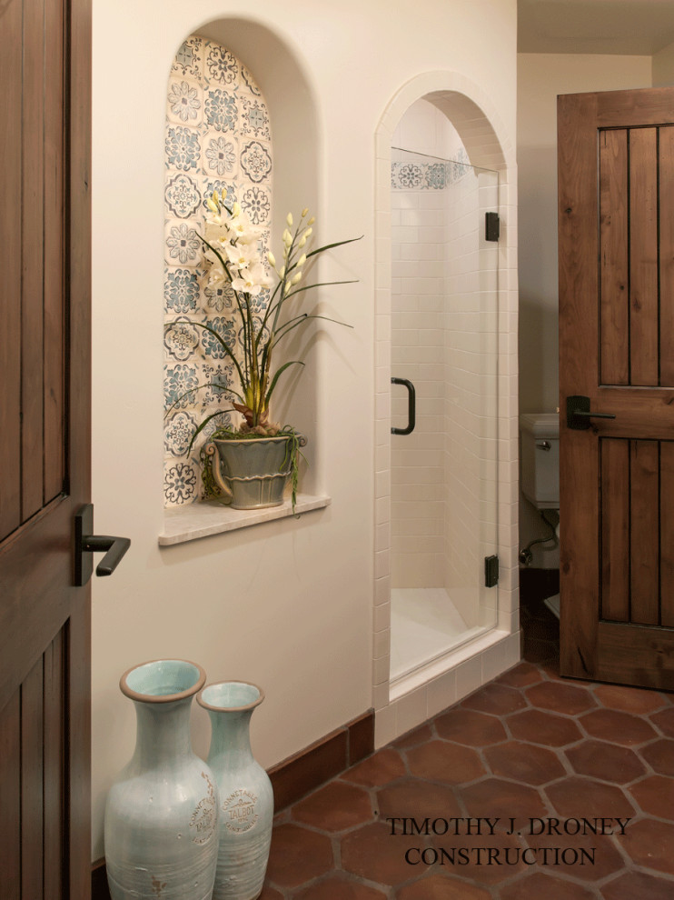 Medelhavsstil inredning av ett litet badrum med dusch, med en hörndusch, vit kakel, keramikplattor, vita väggar, klinkergolv i terrakotta, brunt golv och dusch med gångjärnsdörr
