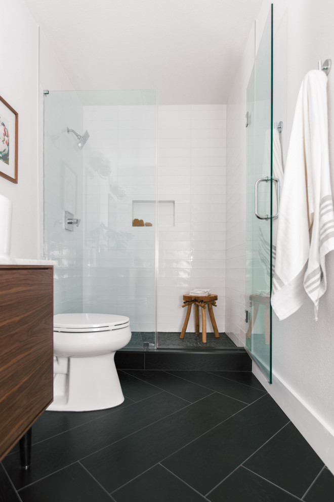 Идея дизайна: маленькая главная ванная комната в скандинавском стиле с плоскими фасадами, коричневыми фасадами, душем в нише, унитазом-моноблоком, белой плиткой, плиткой кабанчик, белыми стенами, полом из керамической плитки, настольной раковиной, столешницей из искусственного кварца, черным полом, душем с распашными дверями, белой столешницей, тумбой под две раковины и напольной тумбой для на участке и в саду