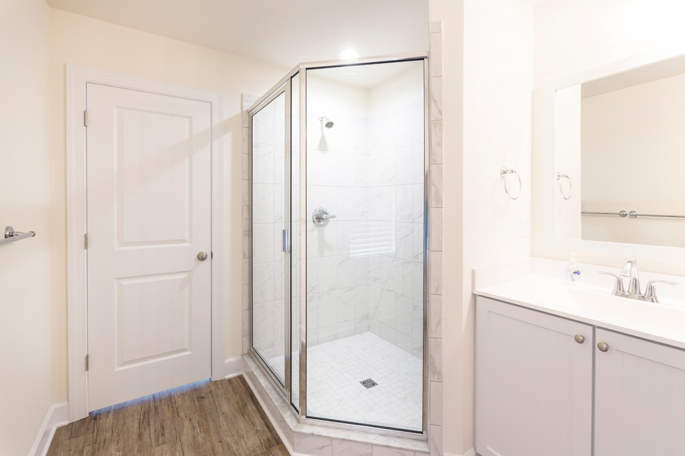 This is an example of a medium sized coastal ensuite bathroom in Other with shaker cabinets, white cabinets, a corner shower, beige walls, dark hardwood flooring, an integrated sink, solid surface worktops, brown floors and a hinged door.