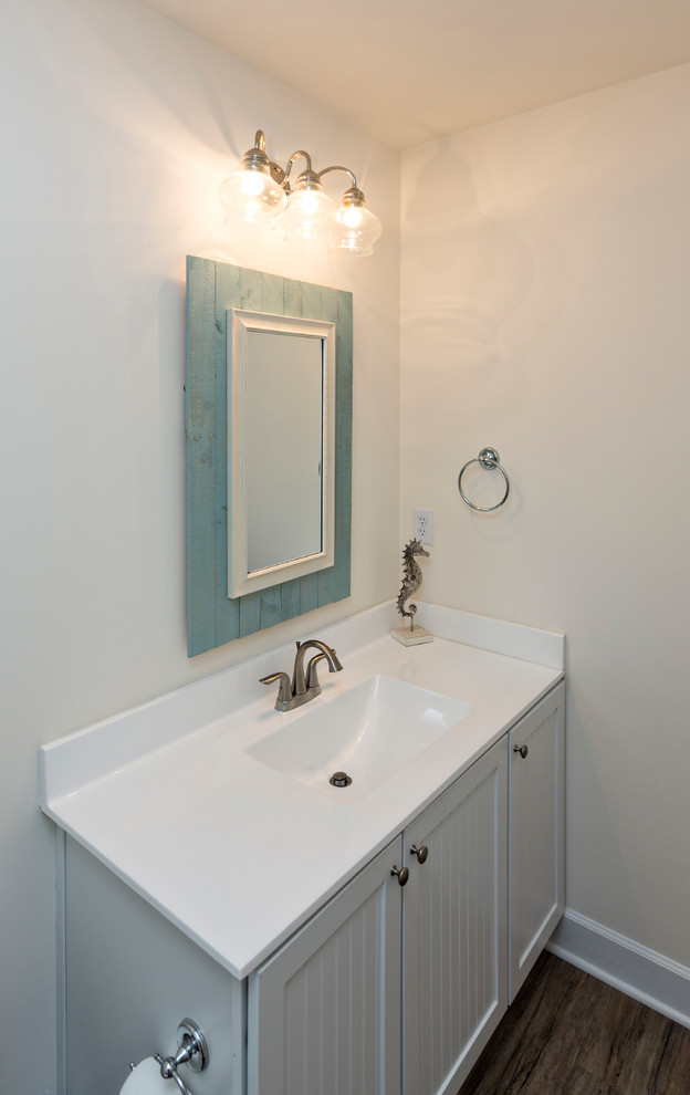 Ispirazione per una stanza da bagno con doccia stile marino di medie dimensioni con ante a persiana, ante bianche, pareti beige, parquet scuro, lavabo integrato, top in superficie solida e pavimento marrone