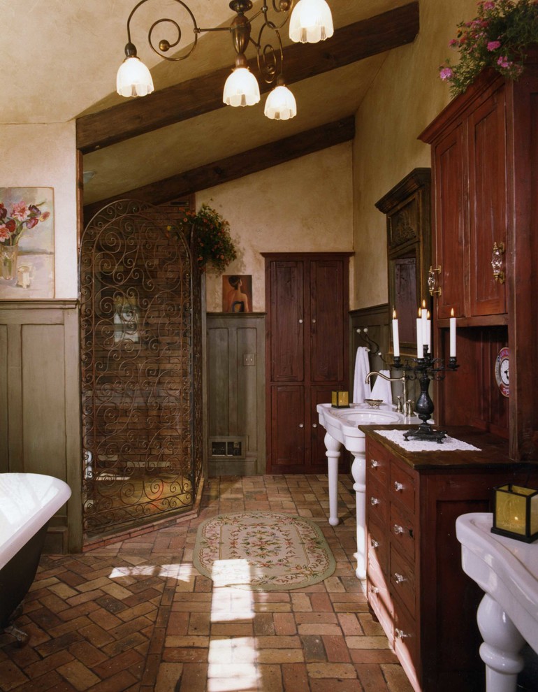 На фото: ванная комната в стиле рустика с ванной на ножках, консольной раковиной и кирпичным полом
