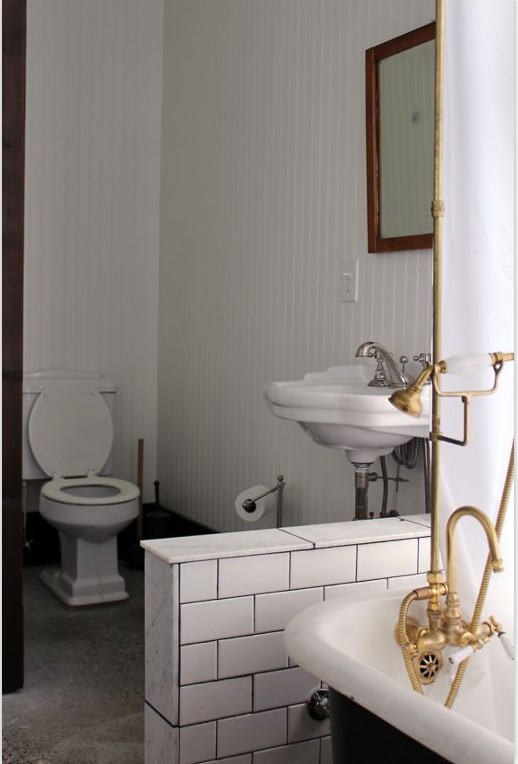 Exempel på ett mellanstort industriellt badrum med dusch, med öppna hyllor, ett badkar med tassar, en dusch/badkar-kombination, en toalettstol med separat cisternkåpa, vit kakel, tunnelbanekakel, vita väggar, klinkergolv i keramik, ett konsol handfat, marmorbänkskiva, svart golv och dusch med duschdraperi