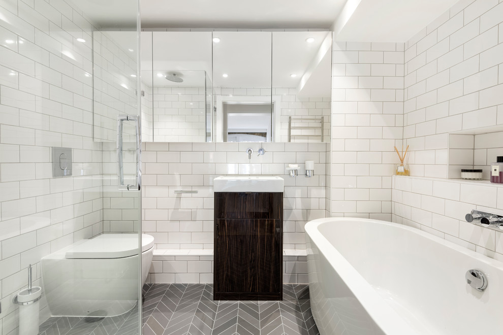 Exempel på ett mellanstort modernt badrum, med släta luckor, bruna skåp, ett fristående badkar, en kantlös dusch, en toalettstol med hel cisternkåpa, tunnelbanekakel, vita väggar, laminatgolv, ett konsol handfat, grått golv och dusch med gångjärnsdörr