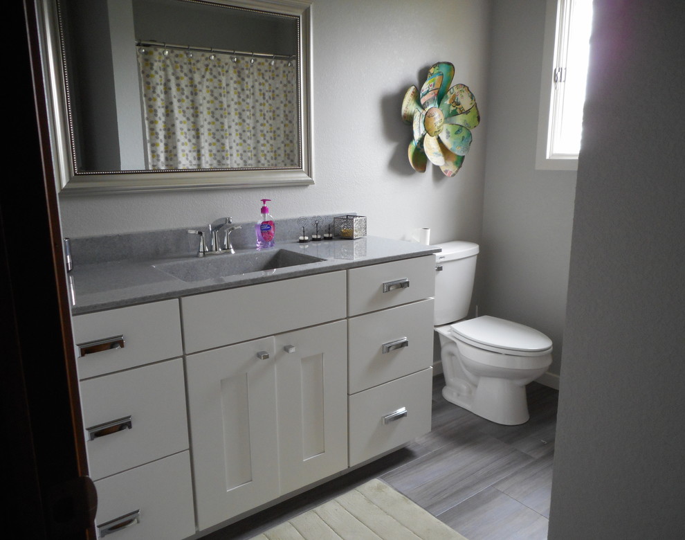 Aménagement d'une salle de bain avec des portes de placard blanches, un sol en carrelage de porcelaine, un lavabo intégré et un plan de toilette en onyx.