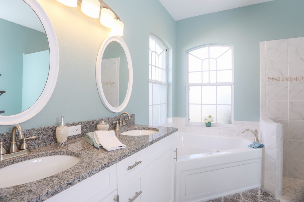 На фото: главная ванная комната среднего размера в классическом стиле с фасадами в стиле шейкер, белыми фасадами, угловой ванной, душем без бортиков, синими стенами, врезной раковиной, столешницей из гранита и открытым душем с