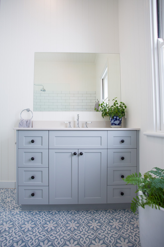 Inredning av ett modernt stort vit vitt en-suite badrum, med möbel-liknande, grå skåp, ett fristående badkar, en hörndusch, en toalettstol med hel cisternkåpa, vit kakel, vita väggar, klinkergolv i keramik, ett nedsänkt handfat, marmorbänkskiva och blått golv