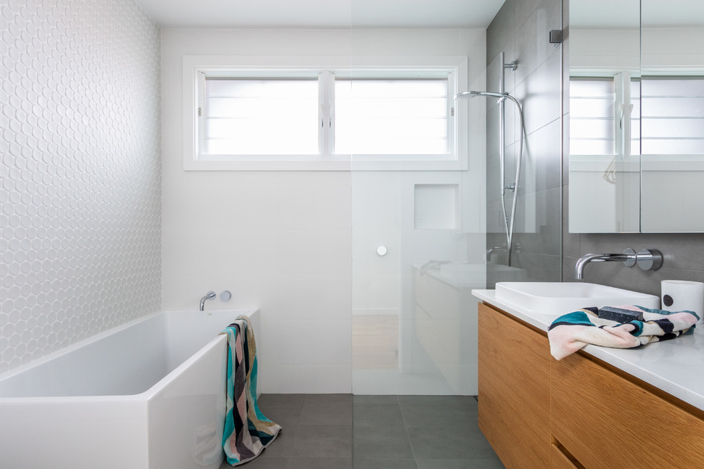 Inspiration for a contemporary wet room bathroom in Sydney with white tiles, grey tiles, ceramic tiles, white walls, ceramic flooring, a built-in sink, engineered stone worktops, grey floors, an open shower, white worktops, flat-panel cabinets, medium wood cabinets and a corner bath.
