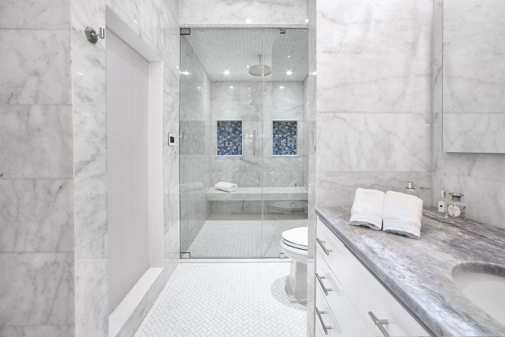 Huge island style master white tile and marble tile marble floor and white floor freestanding bathtub photo in Other with flat-panel cabinets, blue cabinets, a one-piece toilet, white walls, a drop-in sink, marble countertops, a hinged shower door and blue countertops