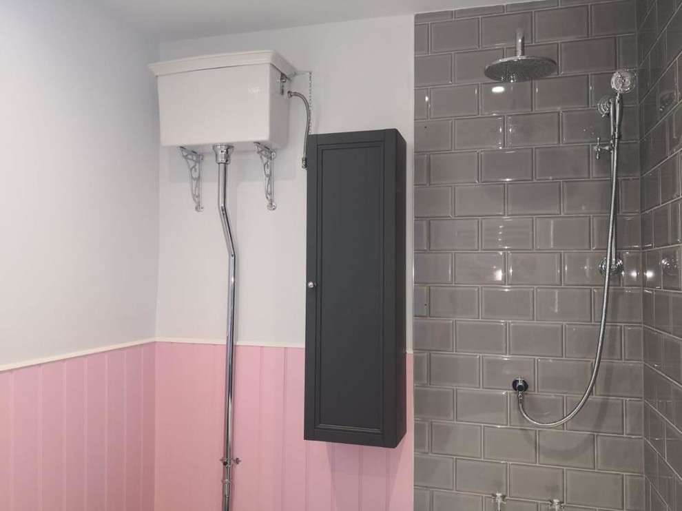 Photo of a medium sized victorian ensuite bathroom in Sussex with shaker cabinets, black cabinets, a freestanding bath, a shower/bath combination, a two-piece toilet, grey tiles, metro tiles, pink walls, porcelain flooring, a built-in sink, beige floors and a hinged door.