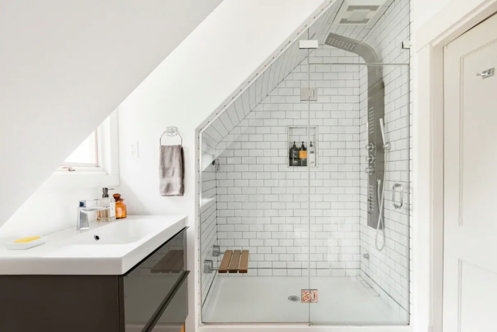 Inspiration for a small retro bathroom in Portland Maine with flat-panel cabinets, grey cabinets, a two-piece toilet, white tiles, metro tiles, white walls, medium hardwood flooring, a submerged sink, solid surface worktops, a hinged door, white worktops, a shower bench, a single sink, a floating vanity unit and a vaulted ceiling.
