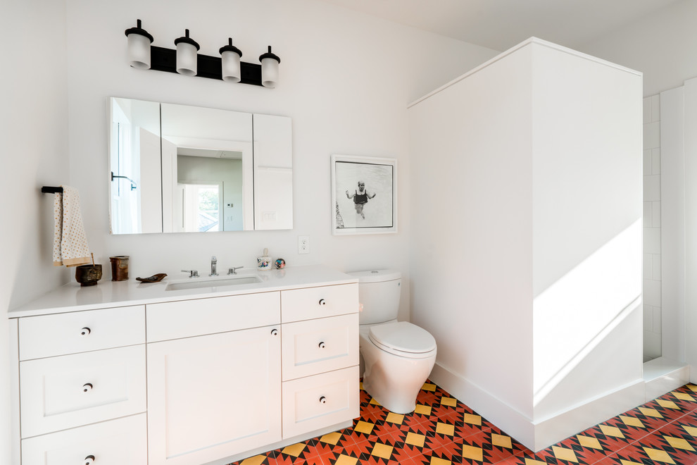 Пример оригинального дизайна: главная ванная комната среднего размера в стиле фьюжн с фасадами в стиле шейкер, белыми фасадами, открытым душем, раздельным унитазом, белой плиткой, керамической плиткой, белыми стенами, полом из цементной плитки, врезной раковиной, столешницей из искусственного кварца, красным полом, открытым душем и белой столешницей