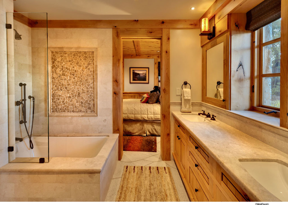 На фото: главная ванная комната в современном стиле с фасадами с выступающей филенкой, светлыми деревянными фасадами, ванной в нише, душем над ванной, бежевой плиткой, плиткой из листового камня и бежевыми стенами